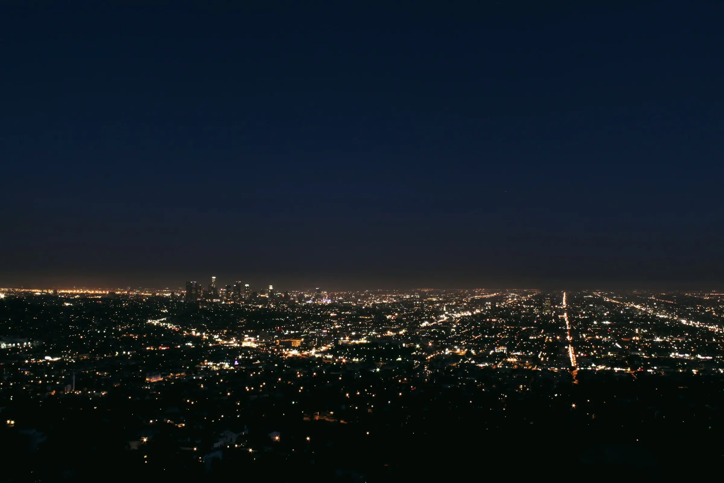 A city grid of lights stretching to the horizon at blue hour
