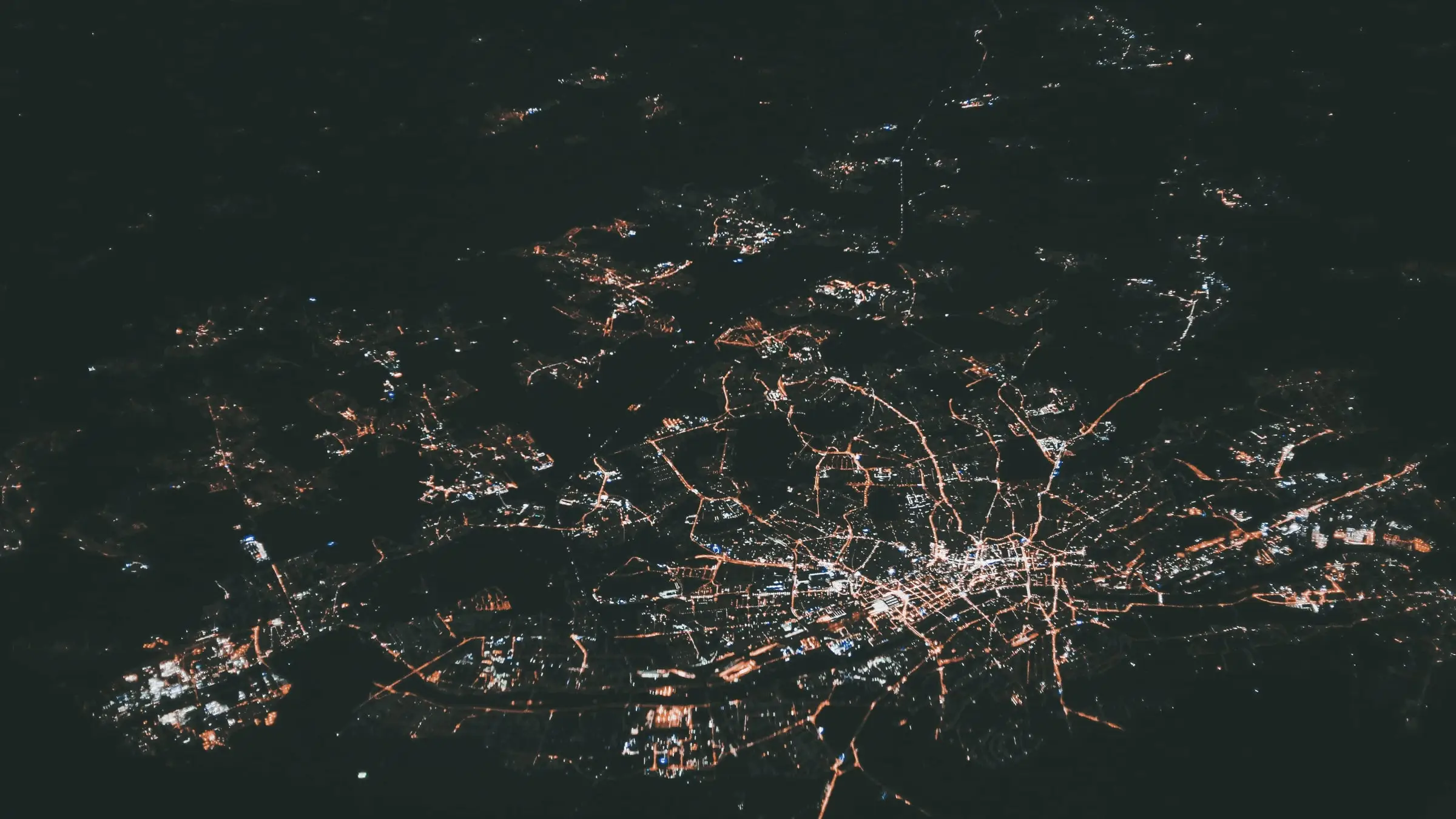 A city's lights at night seen from an aeroplane: streets traced in orange dots across dark land